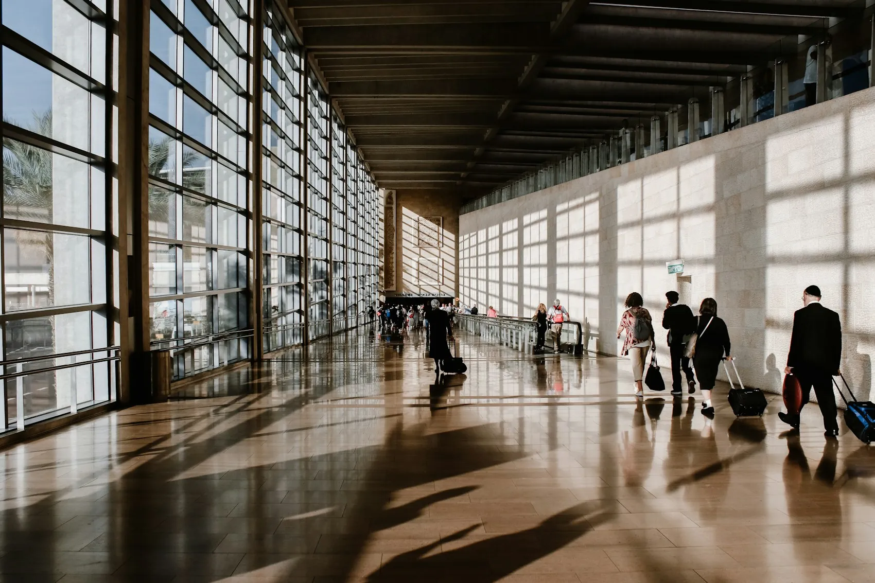 Voyageurs traversant un terminal d'aéroport baigné de lumière, symbole de l'expatriation
